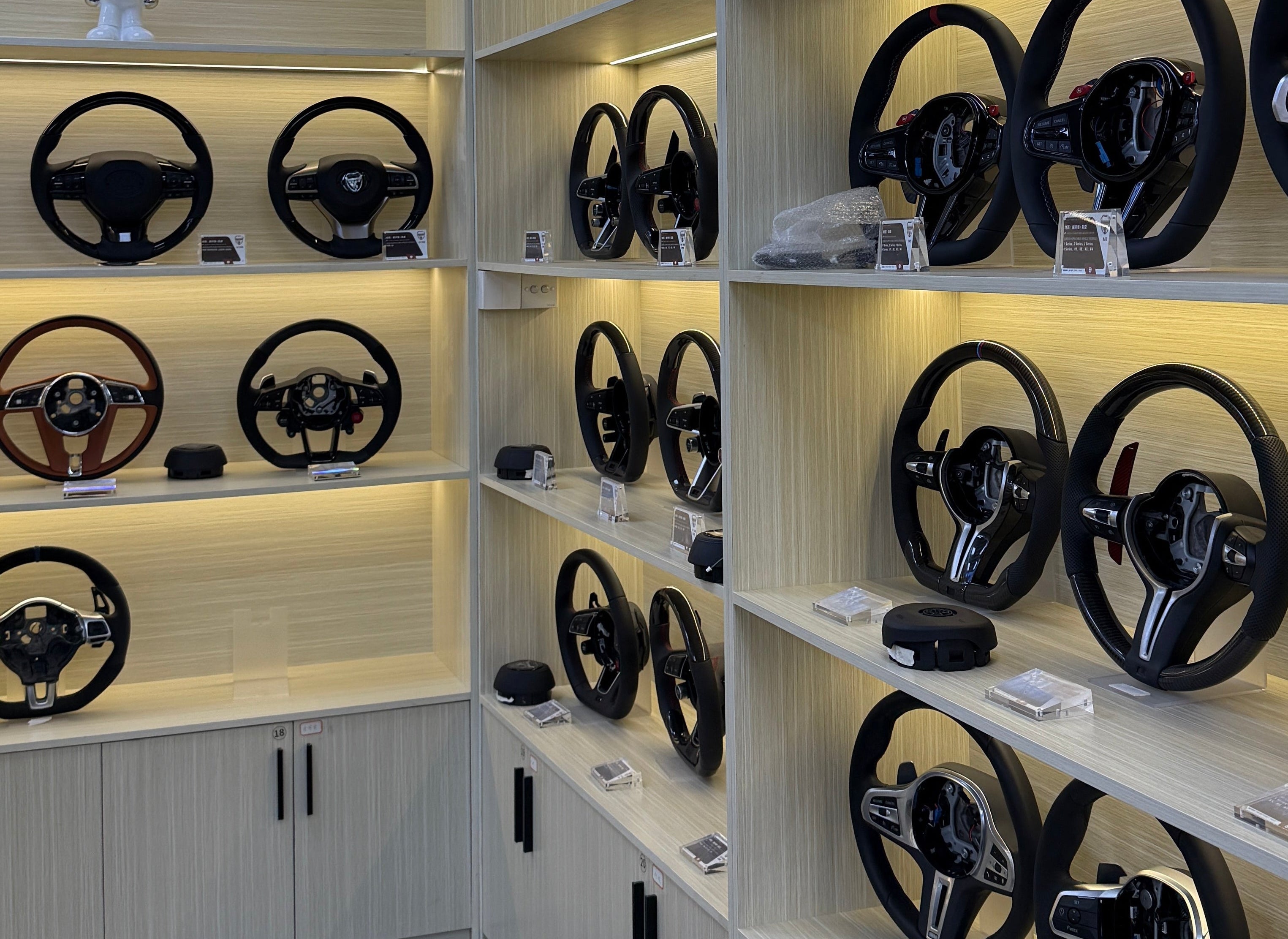 Multiple steering wheels arranged in a grid on a reflective surface.